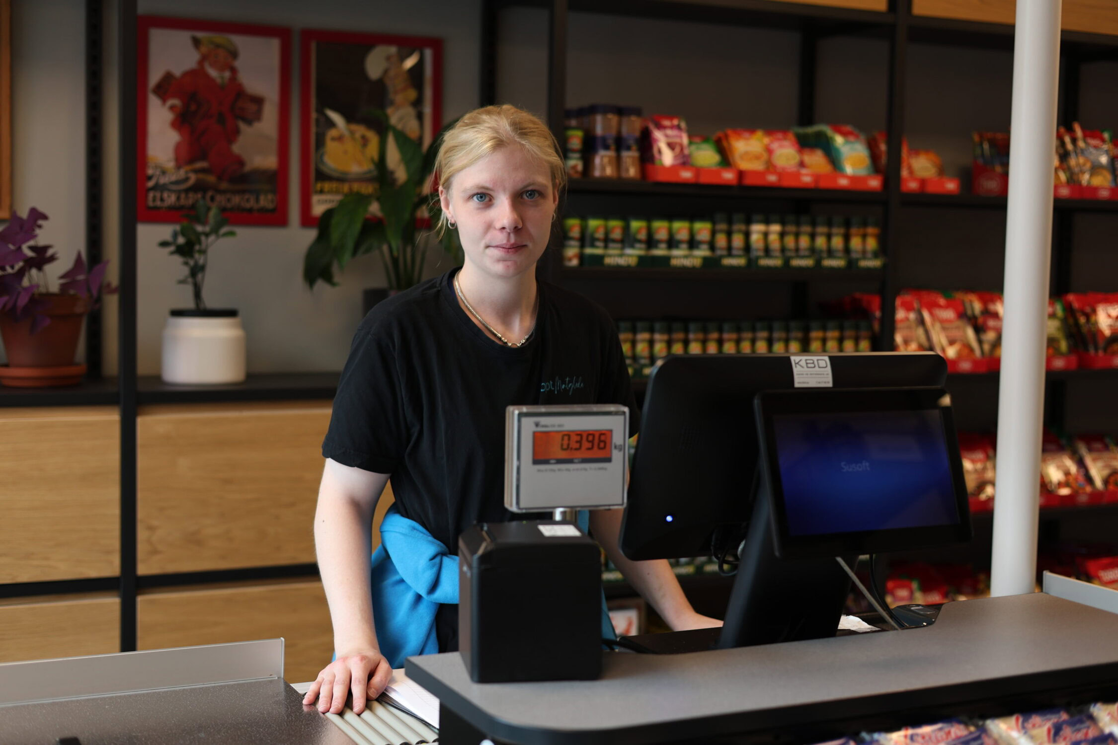 Arbeidstaker som står bak kassen i en butikk