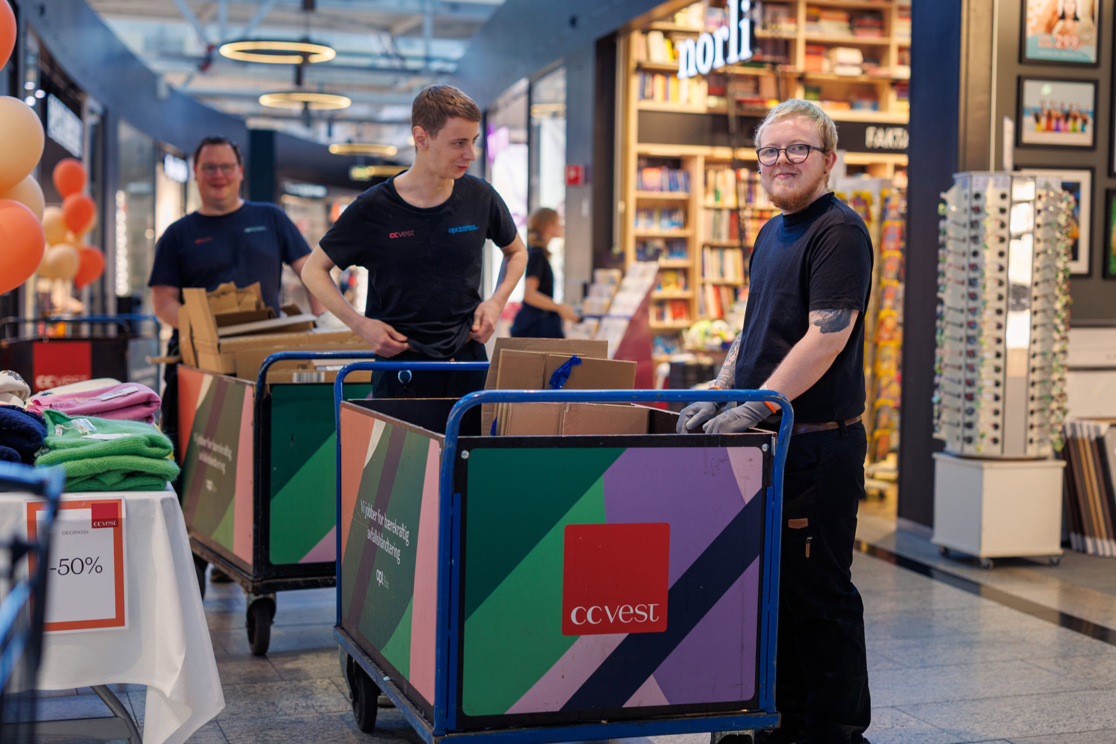 Tre arbeidstakere som henter søppel fra butikker på et kjøpesenter