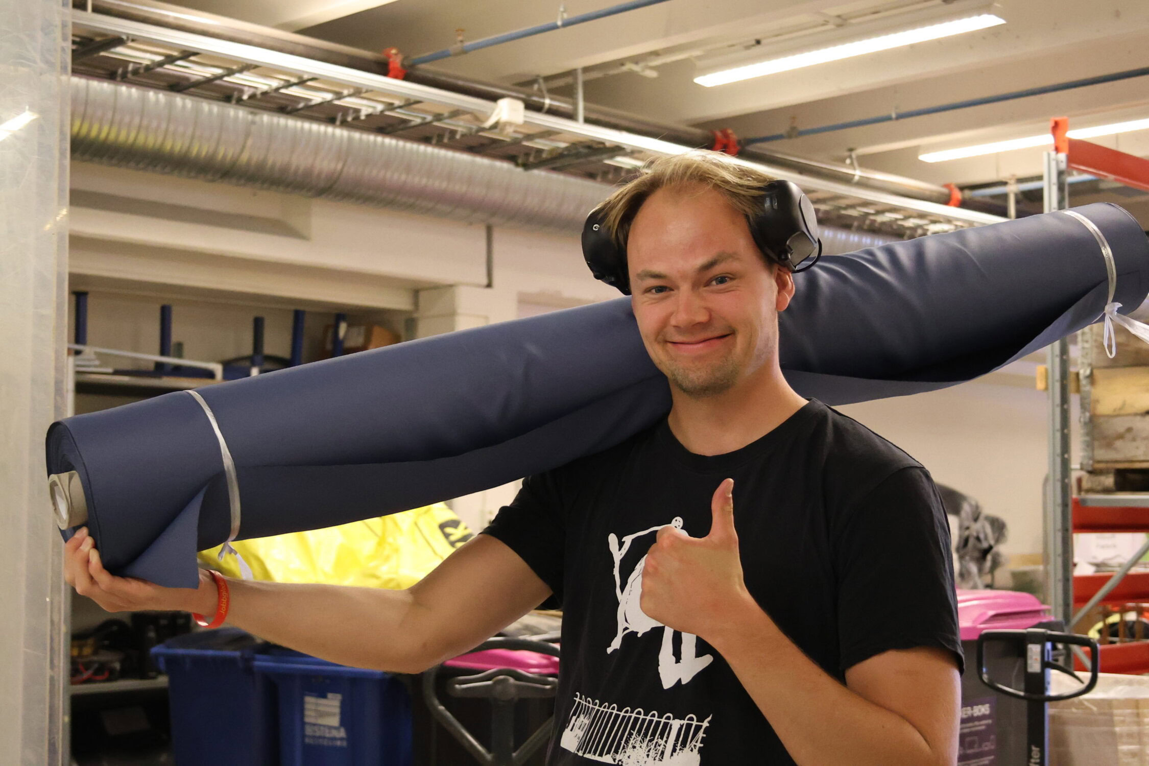 Arbeidstaker som bærer på en stoffrull med et smil